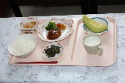 介護施設の食事風景。ご飯、汁物、おかず、副菜がトレーに配置されている